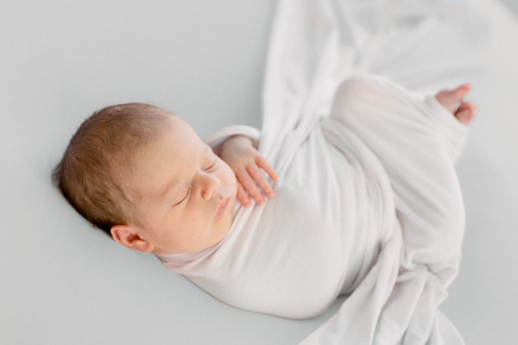 Rolla newborn photographer haven hill studios poses newborn on minimalist clean white bean bag poser for family newborn session