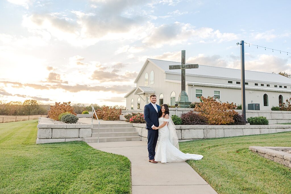 Romantic bride and groom portraits at Red Oak Valley in Owensville Missouri in front of chapel with cross at sunset
